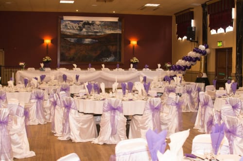 Elegant wedding reception at Sliabh Beagh Hotel with purple chair sashes, white linens, and decorative balloons.