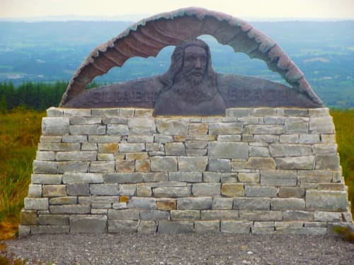 Stone monument with bearded man sculpture and large bronze eagle wings at Sliabh Beagh, Monaghan, Ireland