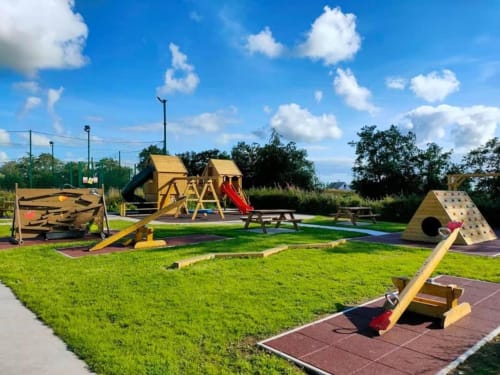 Outdoor adventure playground at Sliabh Beagh Hotel with wooden structures, slides, and climbing equipment on green grass