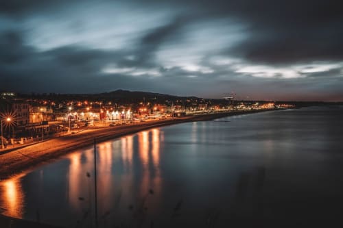 Hilltop Seaview Apartment in Wicklow: Coastal town lit at dusk with beach, harbor lights reflecting on calm water, and