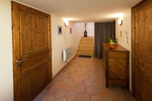 Couloir en bois avec carrelage hexagonal en terre cuite, portes en bois, bureau et escalier vers l'étage au Gîte La Grange