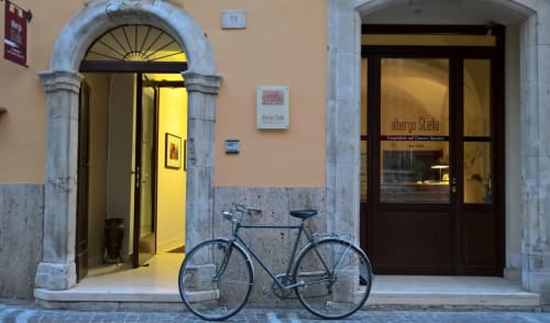 Vélo garé à l'entrée de l'hôtel Albergo Stella à Sulmona, Italie, avec portail en arc et éclairage chaleureux