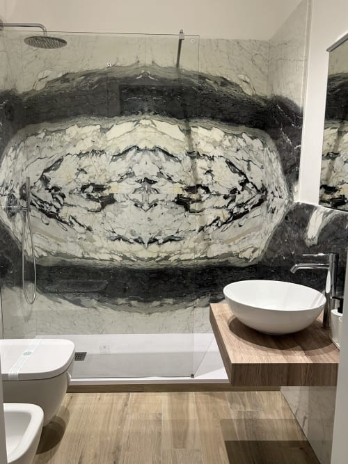 Bagno moderno della BnB Breccia nel Mare con parete in marmo, lavabo da appoggio e doccia a pioggia.
