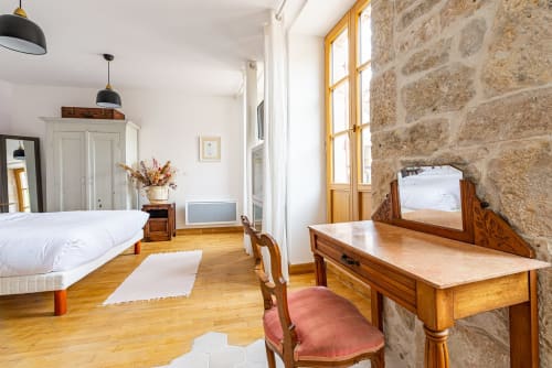 Spacious bedroom at La Maison George with wooden desk, stone wall, and period furniture in Flavigny sur Ozerain