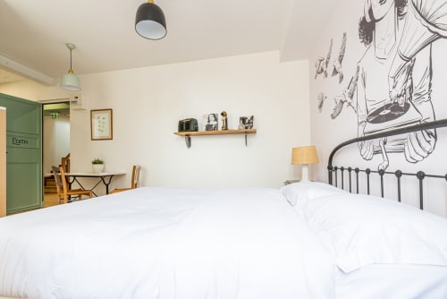Chambre cosy de La Maison George avec literie blanche, lit en métal noir et décoration murale artistique à Flavigny-sur-Ozerain