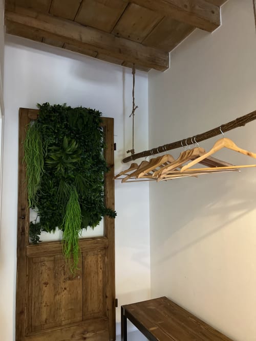 Rustikales Apartmentinterieur mit freiliegenden Holzbalken, grüner Pflanzenwand und Holzgarderobe mit Haken, Bergamo