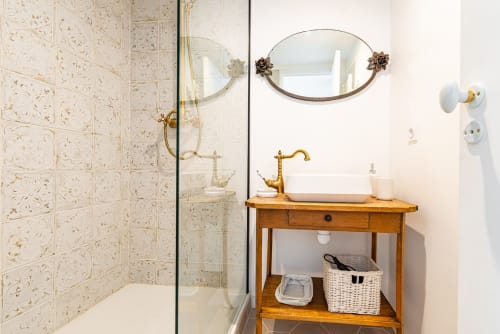 Elegant bathroom in Logis Olympe at La Maison George with wooden vanity, vessel sink, brass faucet, and beige tiled shower