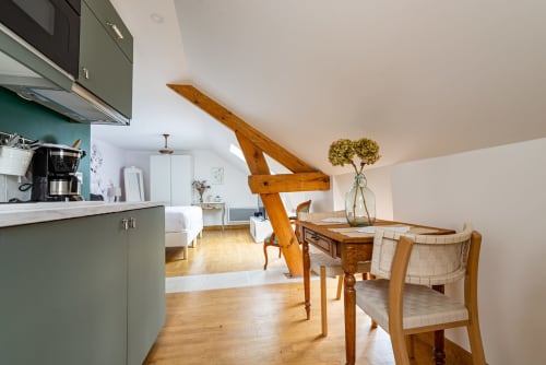 Logis Olympe apartment at La Maison George featuring open-plan kitchen, dining area, wooden beams, and bedroom in Flavigny