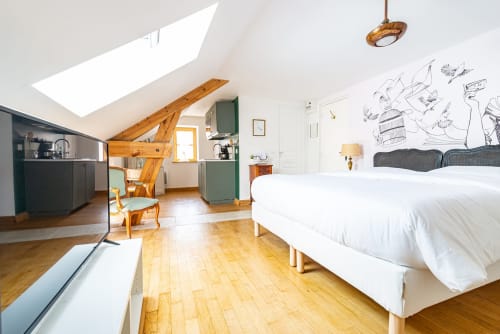 Logis Olympe apartment at La Maison George with wooden beams, white bed, kitchenette, and skylight