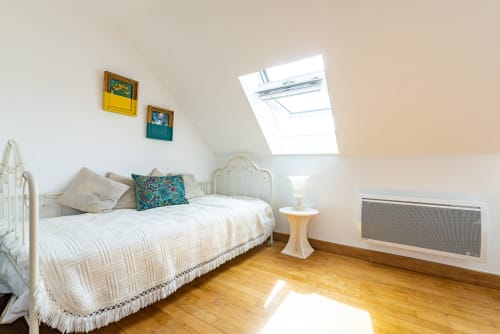 Bright attic bedroom at La Maison George with white iron bed, skylight, wooden floors, and modern amenities in Flavigny sur