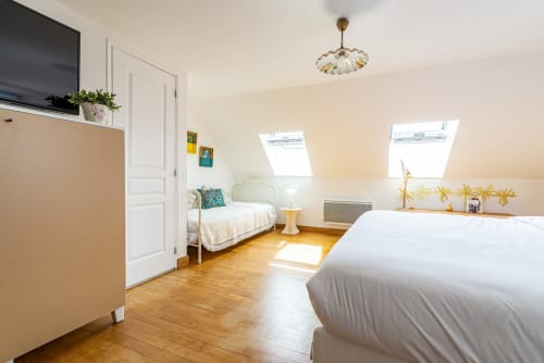 Bright attic bedroom at La Maison George with two beds, skylights, wooden floors, and classic decor