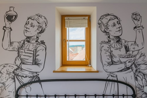 Window view in La Maison George's Logis Marie apartment with vintage female figures wall art and coastal landscape beyond