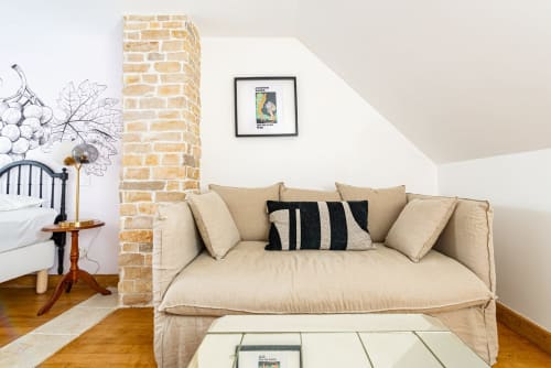 Studio cozy de La Maison George avec canapé crème, colonne en briques apparentes et art contemporain à Flavigny
