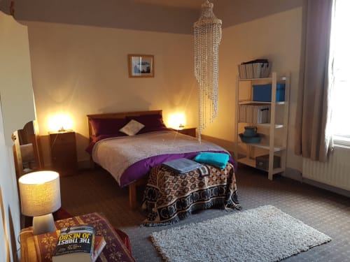 Spacious bedroom at Jane's B&B in Guisborough with wooden bed, warm lighting, shelving, and modern décor