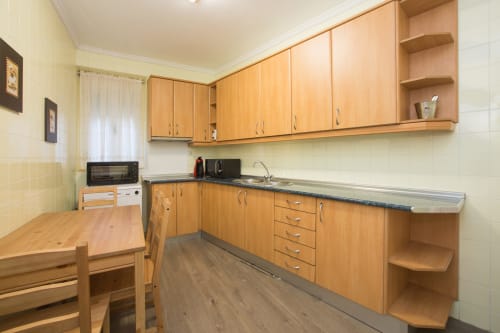 Modern kitchen with wooden cabinets, dark countertops, and dining table at Apartamentos Turísticos Ávila holiday apartment in
