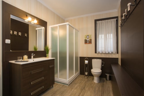 Modern bathroom at Apartamentos Turísticos Ávila with dark vanity, shower enclosure, and toilet in holiday apartment La