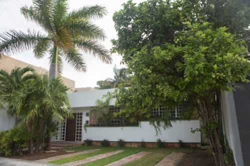 Casa acogedora en el centro de Cancún con fachada blanca, palmeras y paisajismo tropical