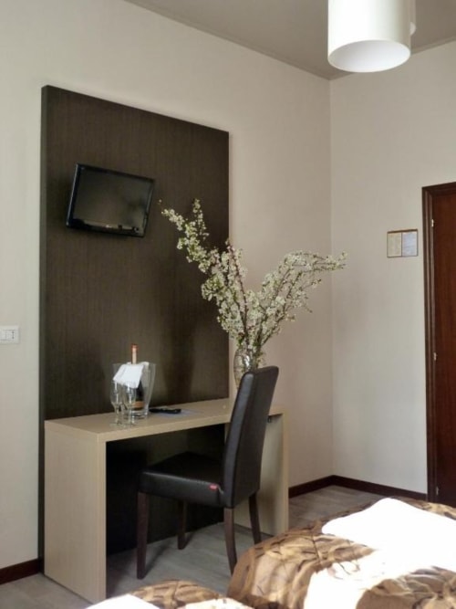 Camera moderna dell'Hotel Eden a Vignola con scrivania, TV a schermo piatto e fiori freschi