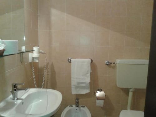 Bagno pulito dell'Hotel Eden a Vignola con piastrelle beige, lavabo bianco, porta asciugamani e toilette