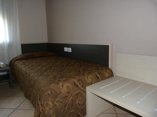 Camera Hotel Eden a Vignola con letto a motivi marroni, testata nera e mobili in legno chiaro
