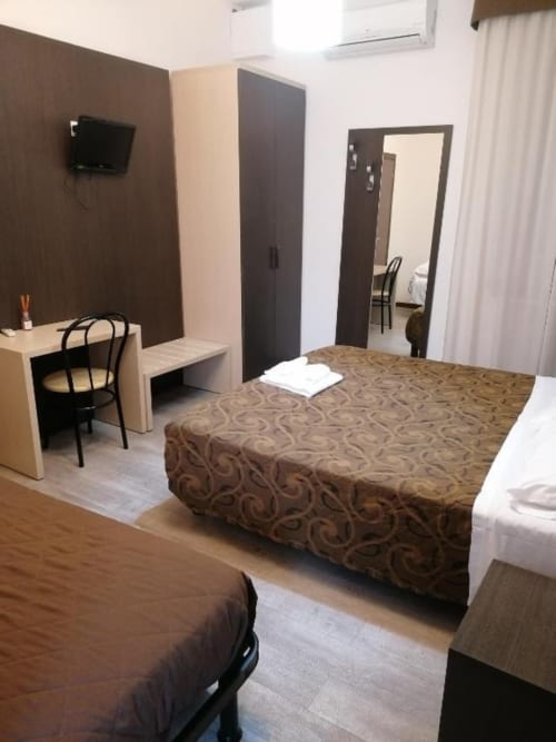 Camera Hotel Eden a Vignola con letti matrimoniali, arredamento moderno e parete scura con TV a muro