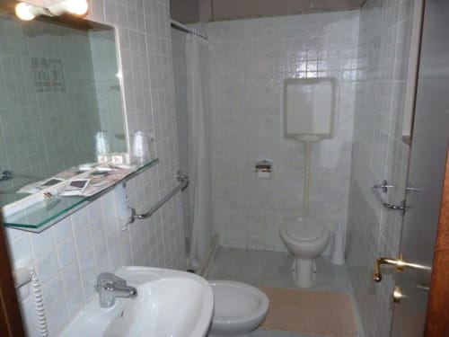 Bagno dell'Hotel Eden a Vignola con lavabo, wc, doccia e rivestimento in piastrelle bianche