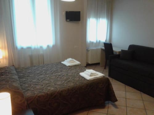 Camera dell'Hotel Eden a Vignola con letto, divano, TV e luminosità naturale dalle finestre