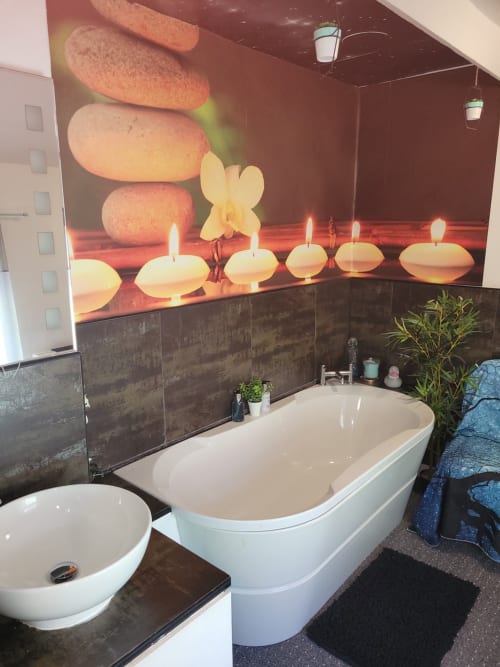 Modern bathroom at Jane's B&B Guisborough with white bathtub, vessel sink, spa-themed wall art with candles and stones, dark