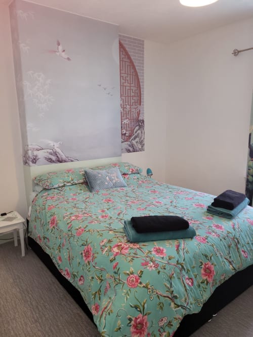Bedroom at Jane's B&B Guisborough with floral turquoise bedding, Asian-inspired wall art, and folded towels on bed