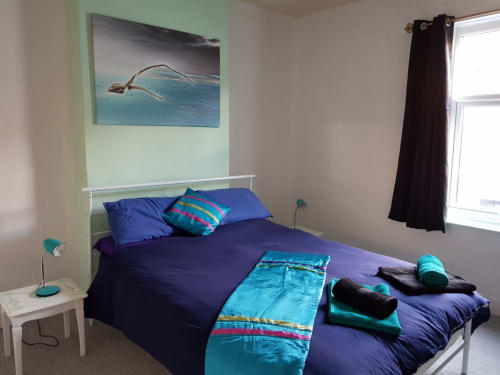 Modern bedroom at Jane's B&B in Guisborough with purple bedding, turquoise accents, white metal bed frame, and coastal