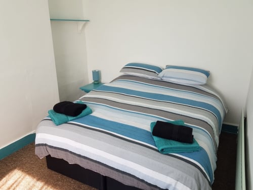 Spacious bedroom at Jane's B&B with striped bedding, turquoise accents, towels, and modern furnishings