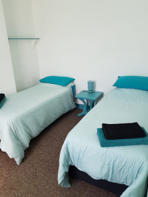 Two single beds with white bedding and teal pillows in a bright bedroom at Jane's B&B villa, Guisborough