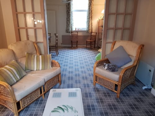 Spacious sitting area in 2-bedroom villa at Jane's B&B Guisborough with cream wicker chairs, blue patterned carpet, and dual