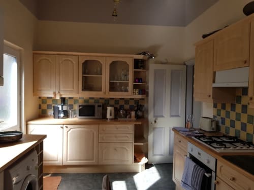 Bright kitchen in Jane's B&B villa with wooden cabinets, gas cooker, patterned backtile, and modern appliances in Guisborough