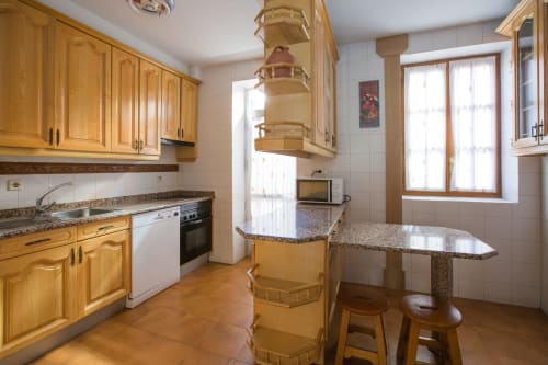 Amplia cocina en Apartamentos Turísticos Ávila con muebles de madera, encimeras de granito e isla central