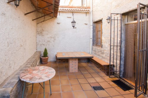 Patio de Apartamentos Turísticos Ávila con baldosas de terracota, mesa de madera, plantas en maceta y muros encalados