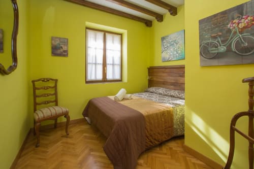 Dormitorio amarillo brillante en Apartamentos Turísticos Ávila con cama de madera, piso en espiga y vistas a la ciudad