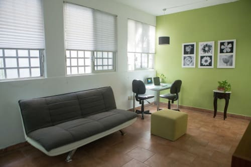 Moderna sala de estar en Cozy House Downtown Cancún con sofá negro, pared verde y área de trabajo