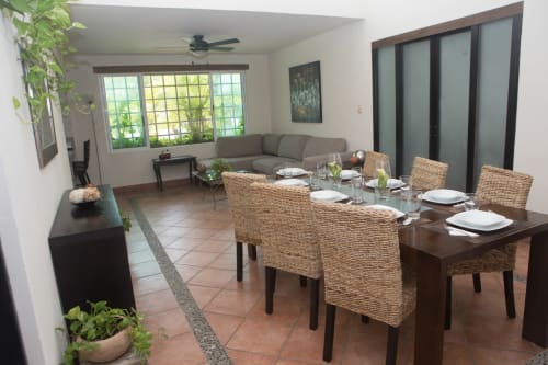 Casa acogedora en el centro de Cancún con sala y comedor integrados, sillas tejidas, mesa de madera y sofá gris