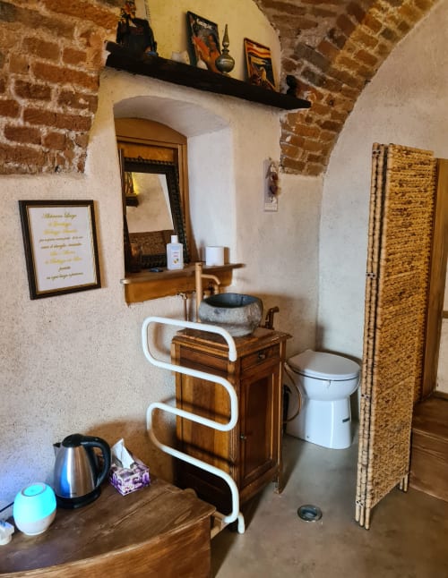 Bagno rustico nella camera romantica CasaRosada a Vidracco, Italia con vanità in legno, lavabo in pietra, wc e porta asciugamani bianco