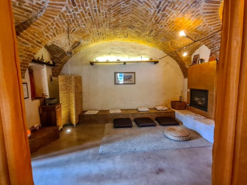 Camera romantica CasaRosada a Vidracco con volta a botte in mattoni, cuscini da pavimento, camino e arredamento rustico