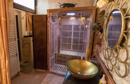 Luxurious bathroom in CasaRosada cottage, Vidracco, featuring gold vessel sink, infrared sauna, heated towel racks and ornate