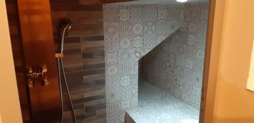 Modern shower with striped tile walls and decorative mosaic floor in CasaRosada cottage bathroom, Vidracco Italy