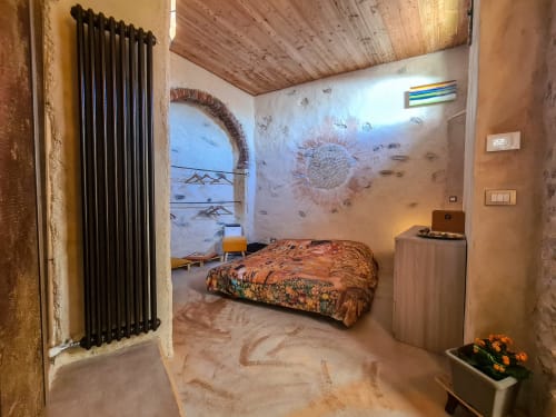 Rustic bedroom at CasaRosada ALCHIMIA in Vidracco with wooden ceiling, patterned bedding, and garden views