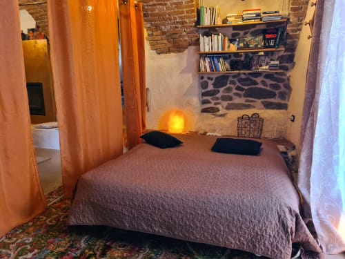 Cozy bedroom at CasaRosada cottage in Vidracco with exposed stone walls, orange curtains, and garden view