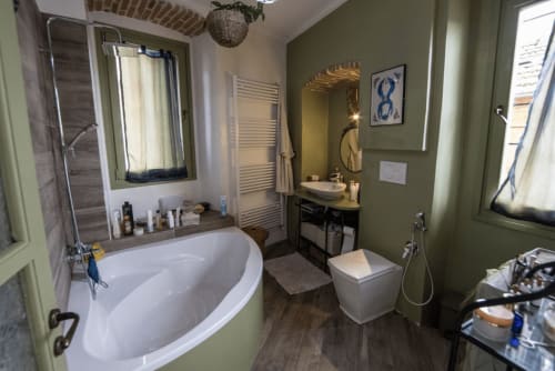 Modern bathroom at CasaRosada wellness retreat in Vidracco with bathtub, shower, vanity, and sage green walls