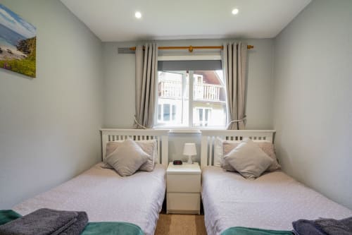Cornish Holiday - 91 Hengar Manor. The twin bedroom with single beds, bedside cabinet, lamp and clock. Complimentary towels.
