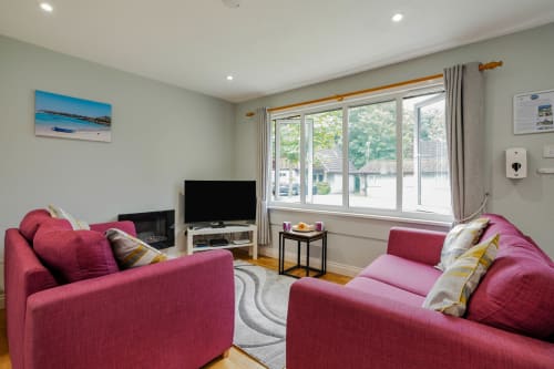 Cornish Holiday - 91 Hengar Manor.  Open plan lounge with two sofas, flame effect electric fire smart TV, rug coffee tables and large window looking outside.