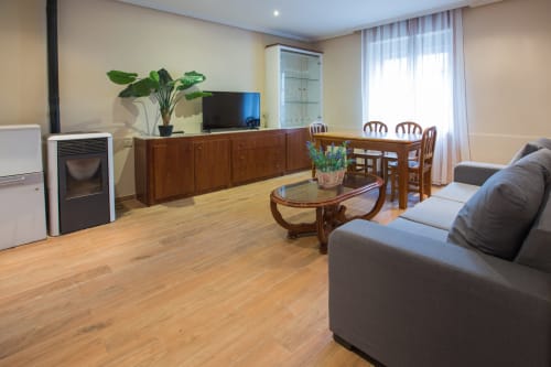 Amplia sala de estar en apartamento VILLA CARMEN III, Ávila con muebles de madera, sofá gris, mesa de comedor y mueble TV