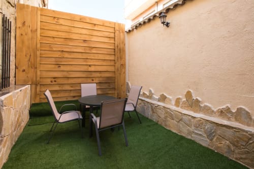 Patio privado de Apartamentos Turísticos Ávila con césped artificial, zona de descanso, cerca de madera y muros de piedra
